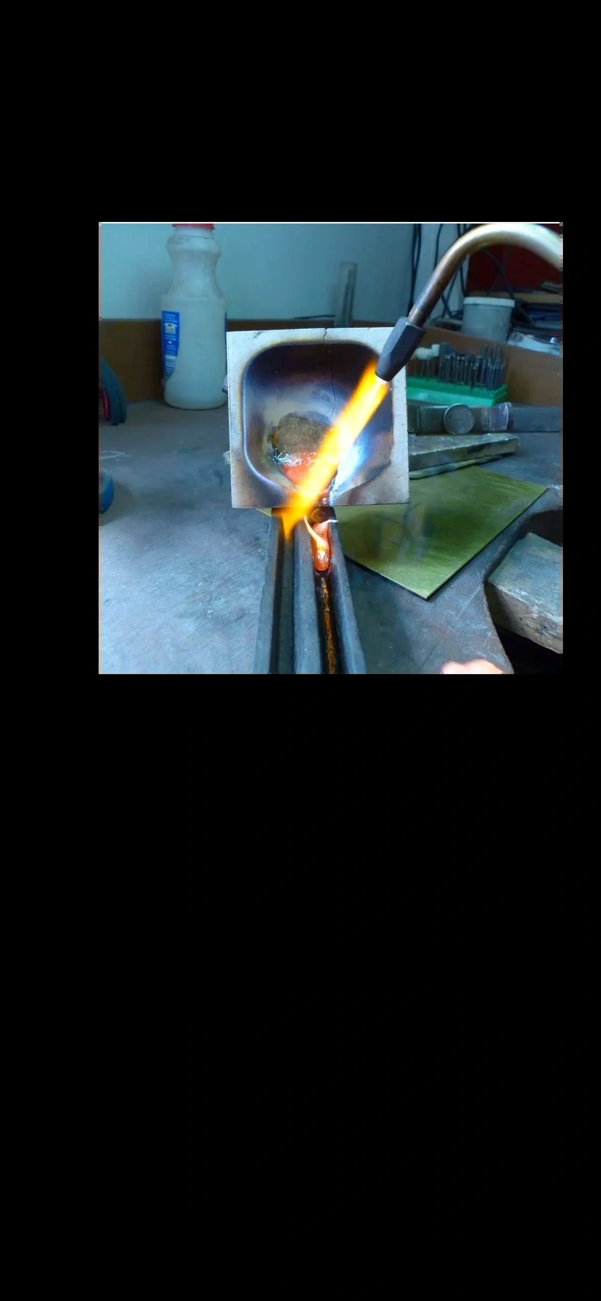 The torch flame at the Jody Cory bench, soldering a piece of gold stock at the anvil.